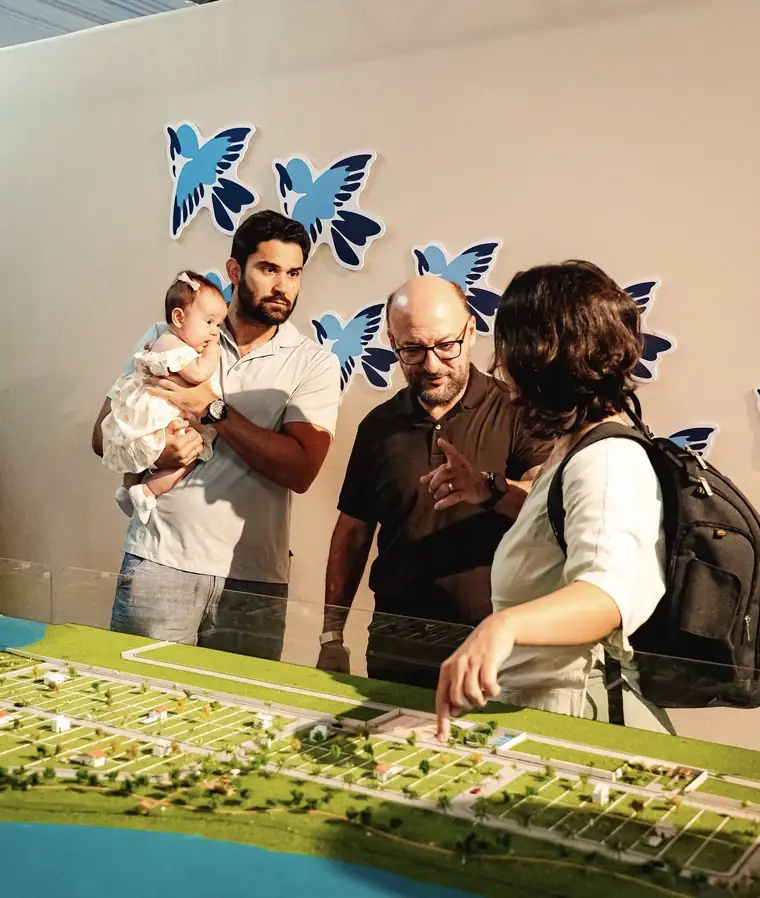 Família conhecendo a maquete do Vila dos Pássaros no lançamento