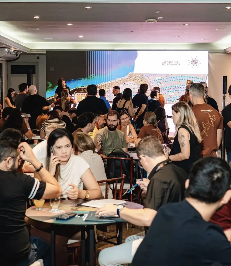 Salão do Ideal Clube cheio durante o lançamento, com o mapa de disponibilidade projetado