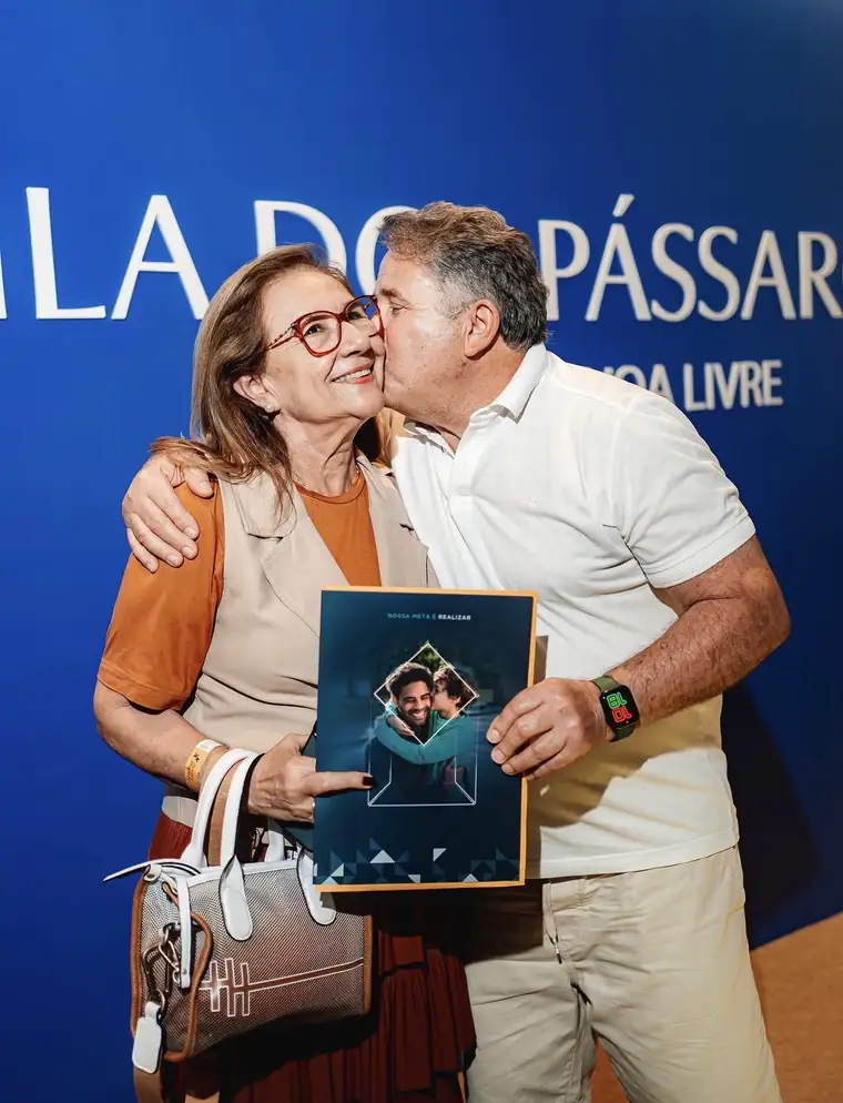 Casal comemorando a compra do lote no painel do Vila dos Pássaros